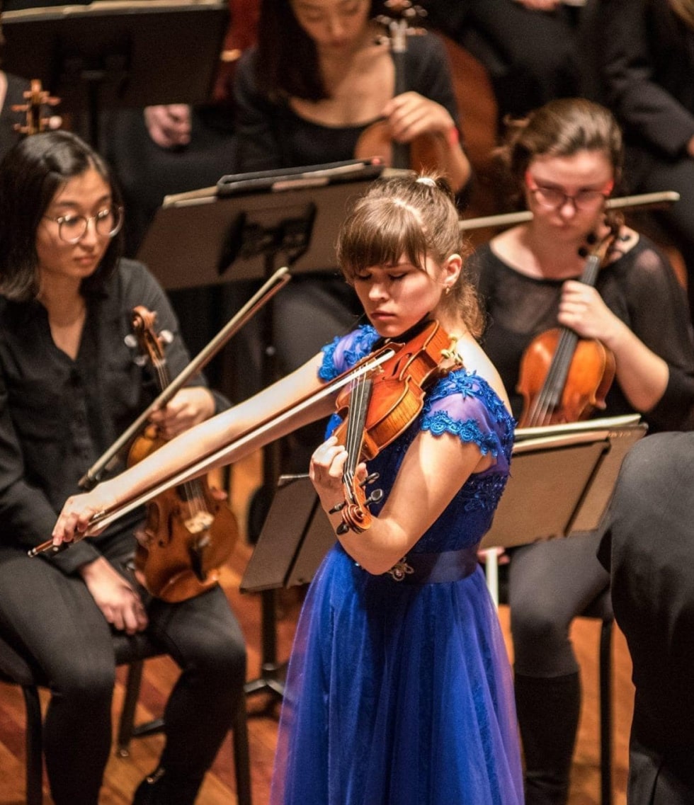 Hanna is playing with orchestra in blue dress