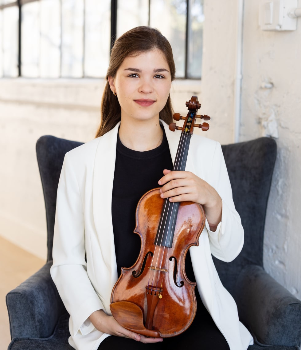 Hanna is sitting with a violin on a chair